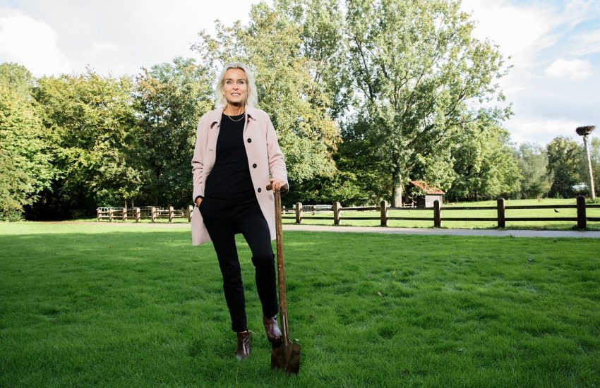 Barbara Baarsma met schep in hand op een grasveld